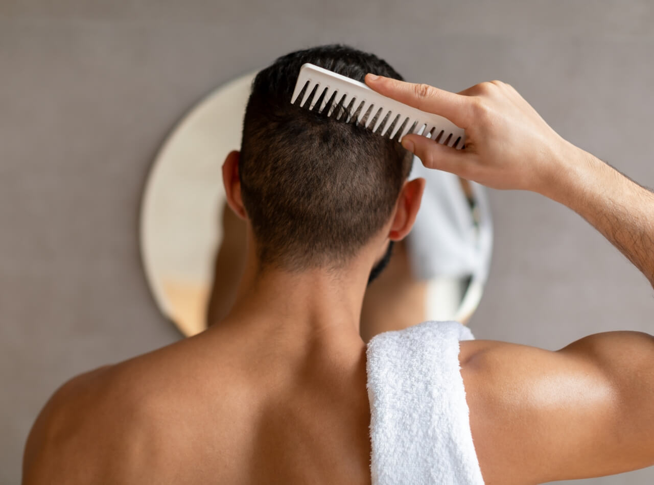 back-view-of-young-man-looking-in-mirror-brushing-2023-11-27-05-23-38-utc (1)